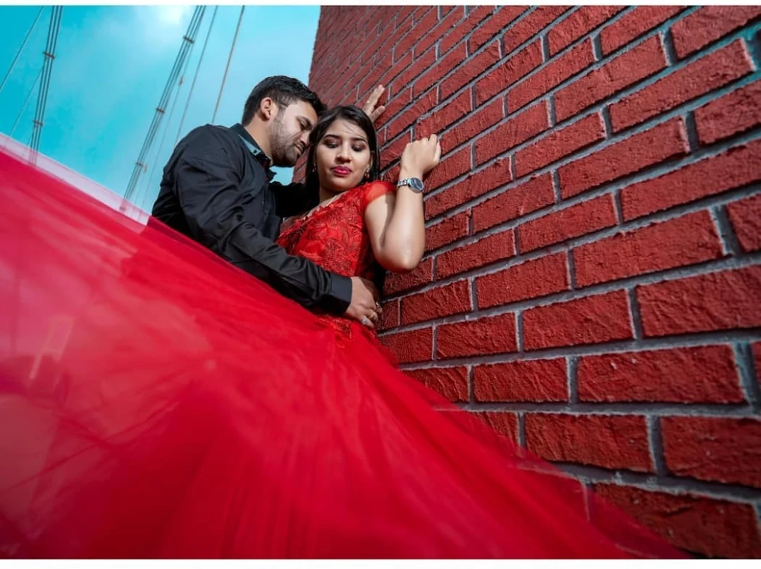 Red flowy gown prewedding shoot against brick wall